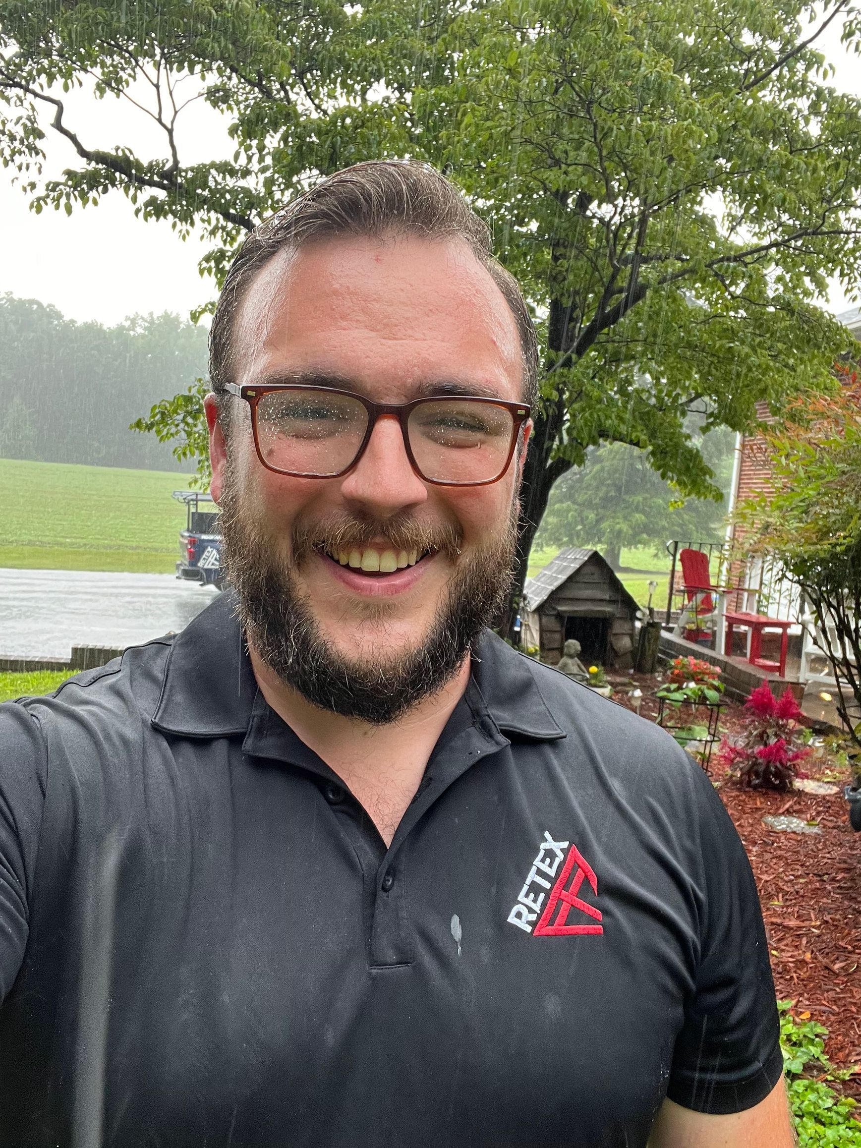 A photo of RETEX's Andy Connor drenched in the rain during a roof replacement appointment.