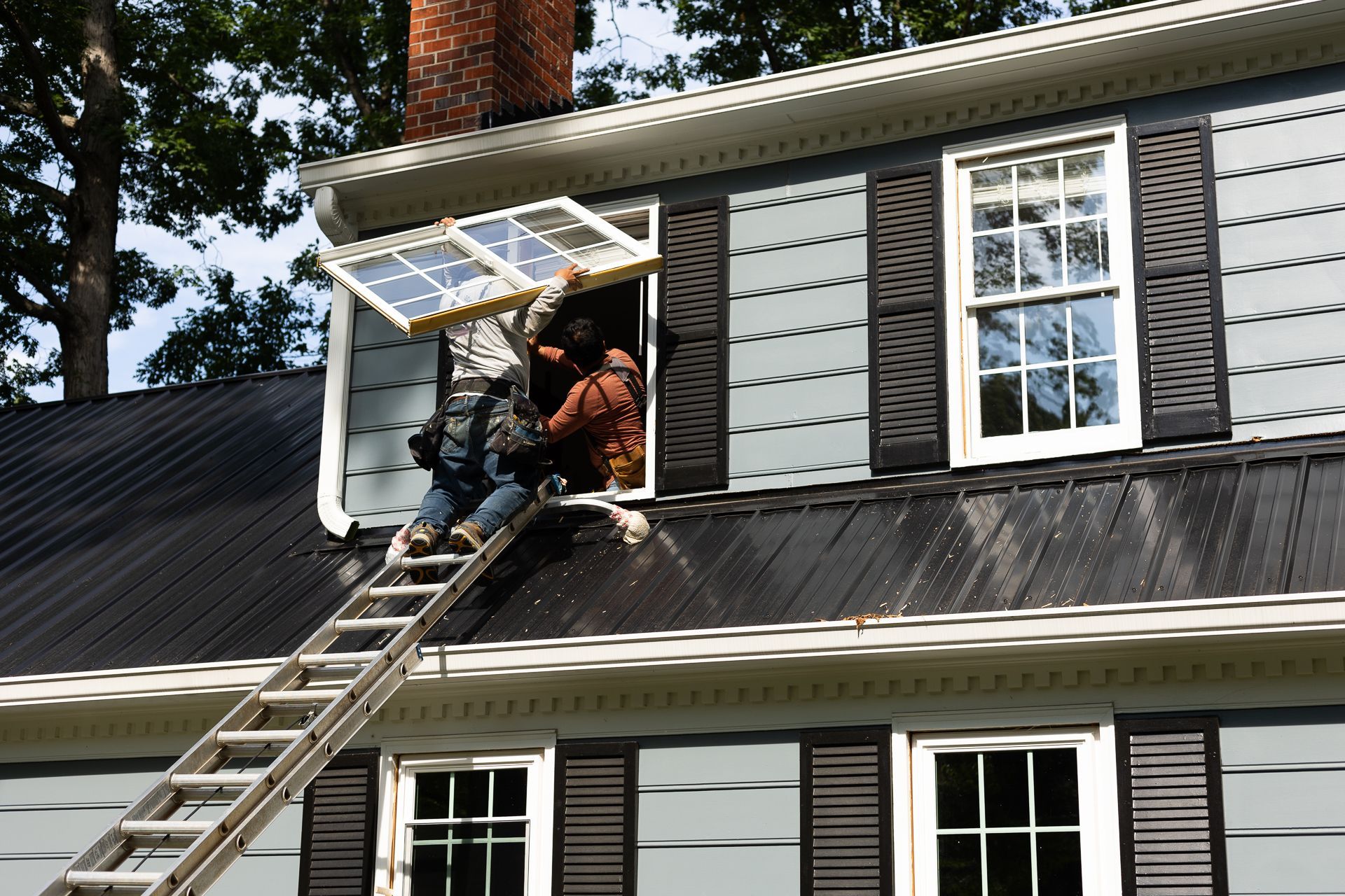 A RETEX window installer carries a new low-E fiberglass window to second floor, North Chesterfield.