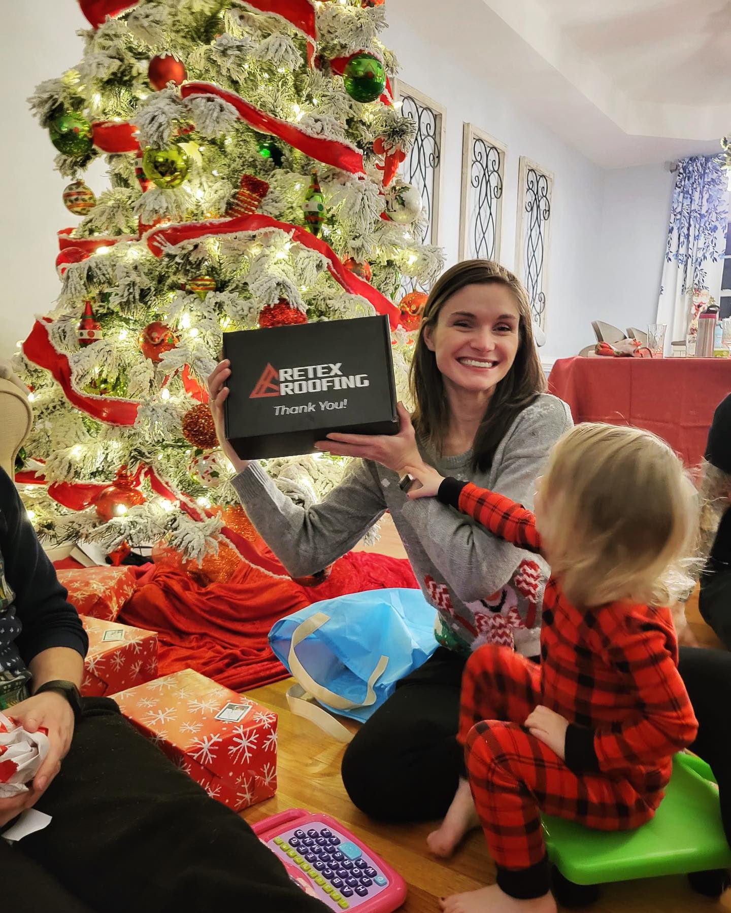 A photo client's daughter in front of a Christmas tree, holding a RETEX box that was re-used for a present.