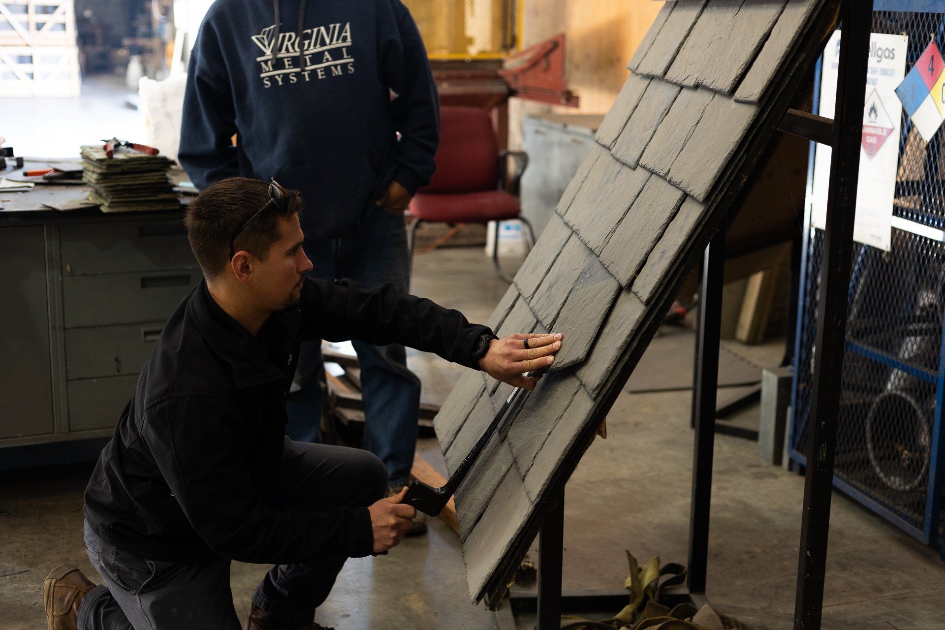 An image of RETEX's Caleb Kammerling installing natural slate on a roof template during a team training event.