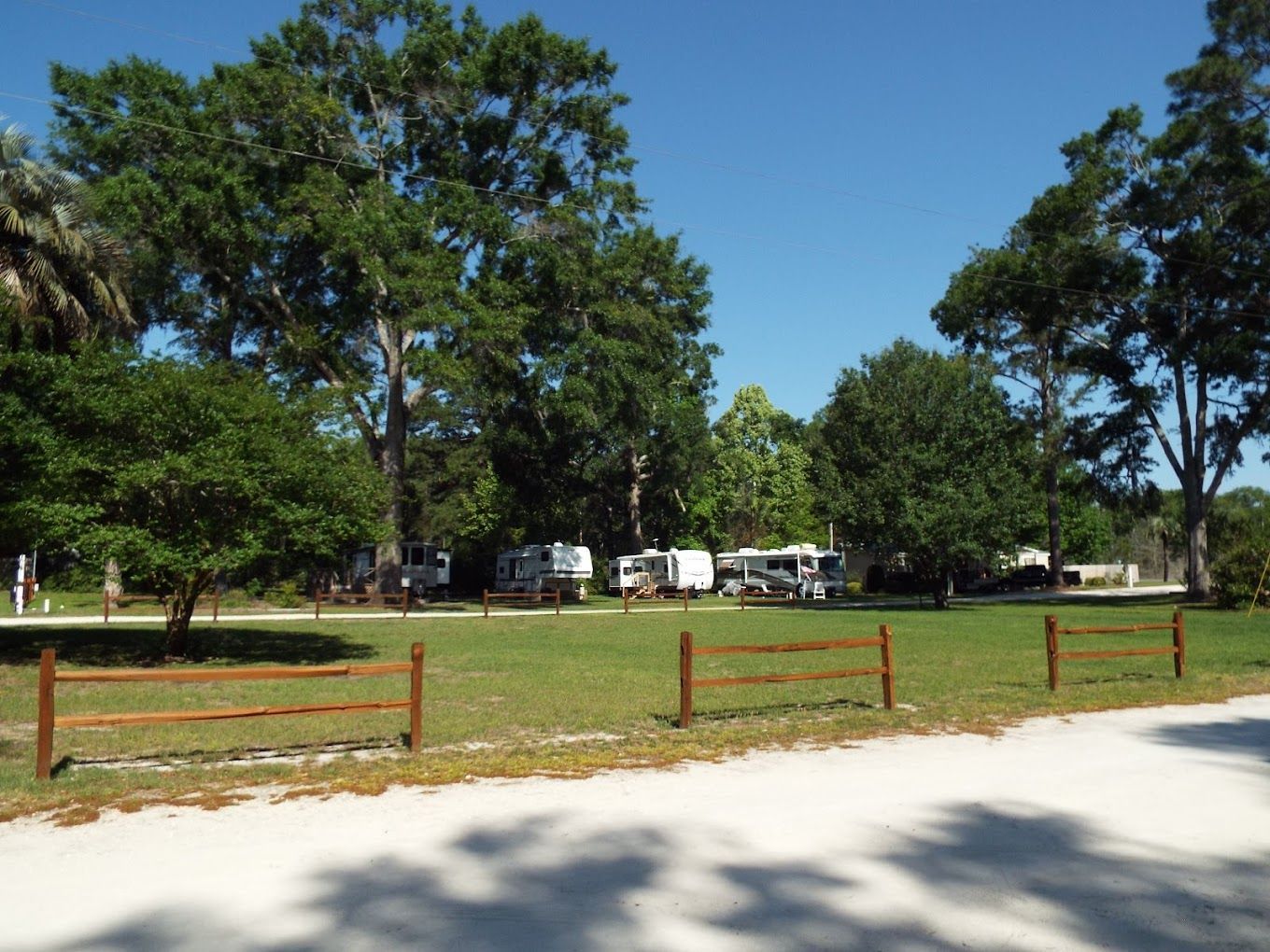 A wooden fence surrounds a grassy field with trees