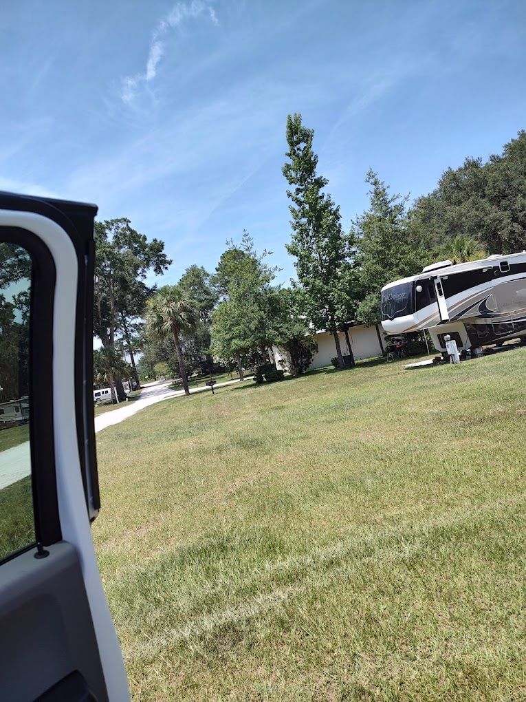 A rv is parked in a grassy field next to a house.