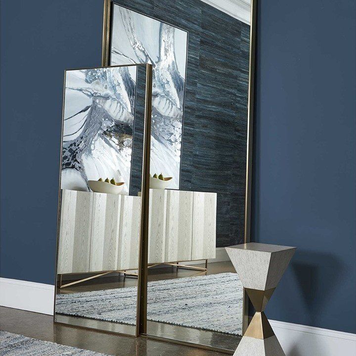 Deep blue walls with gold mirrors and marble side stand decor