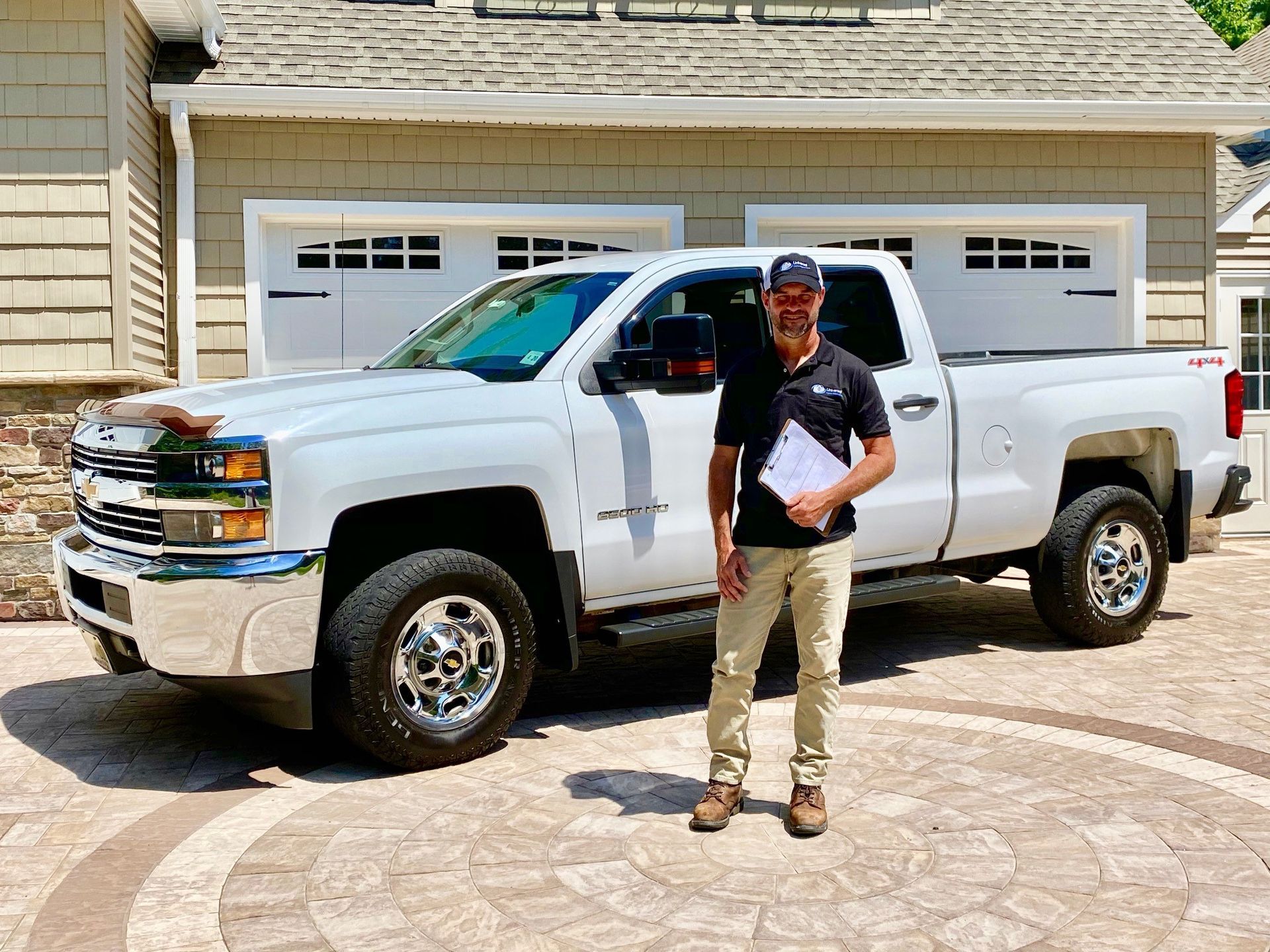 A man is standing in front of a white truck in front of a house.