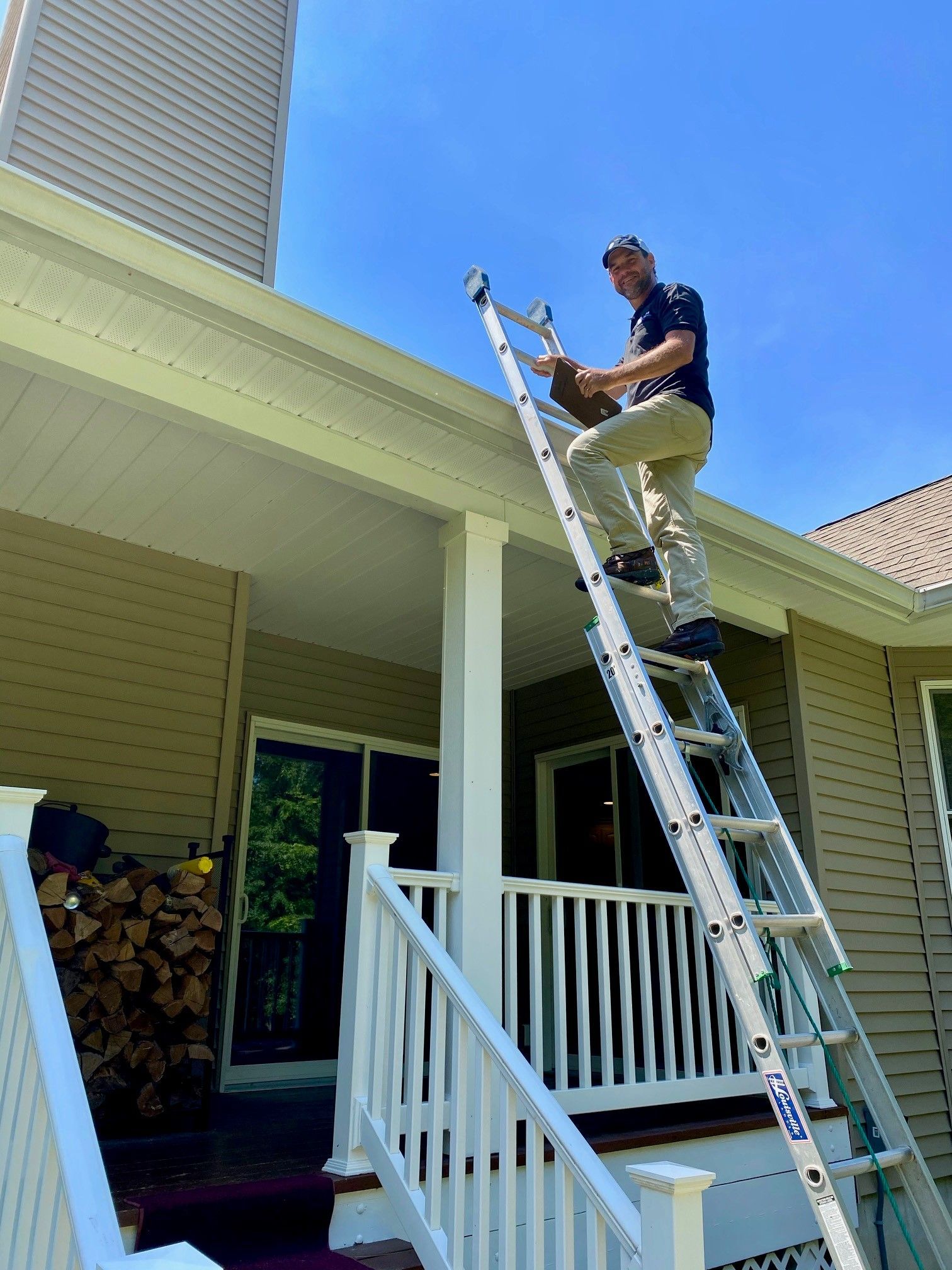 A man is standing on a ladder on the porch of a house.