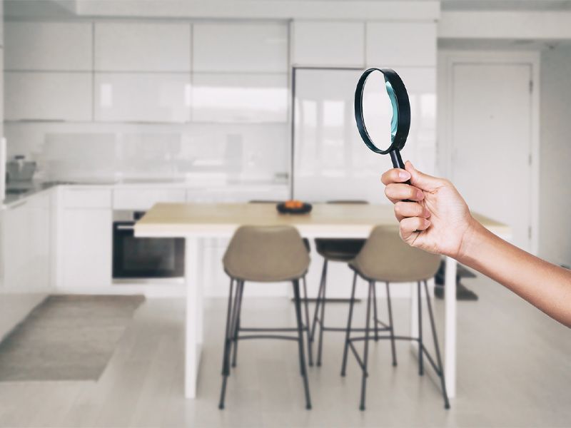 A person is holding a magnifying glass in front of a kitchen.