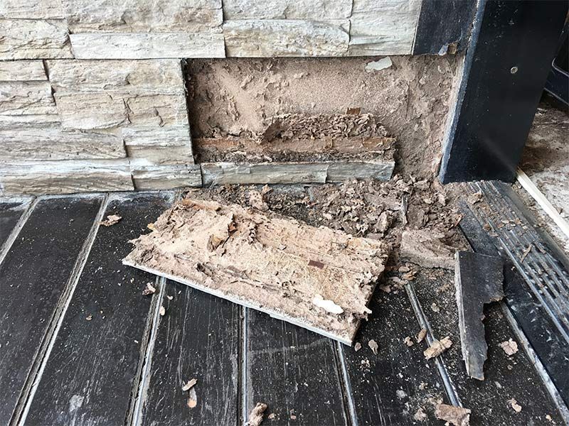 A piece of wood is laying on a wooden floor next to a brick wall.