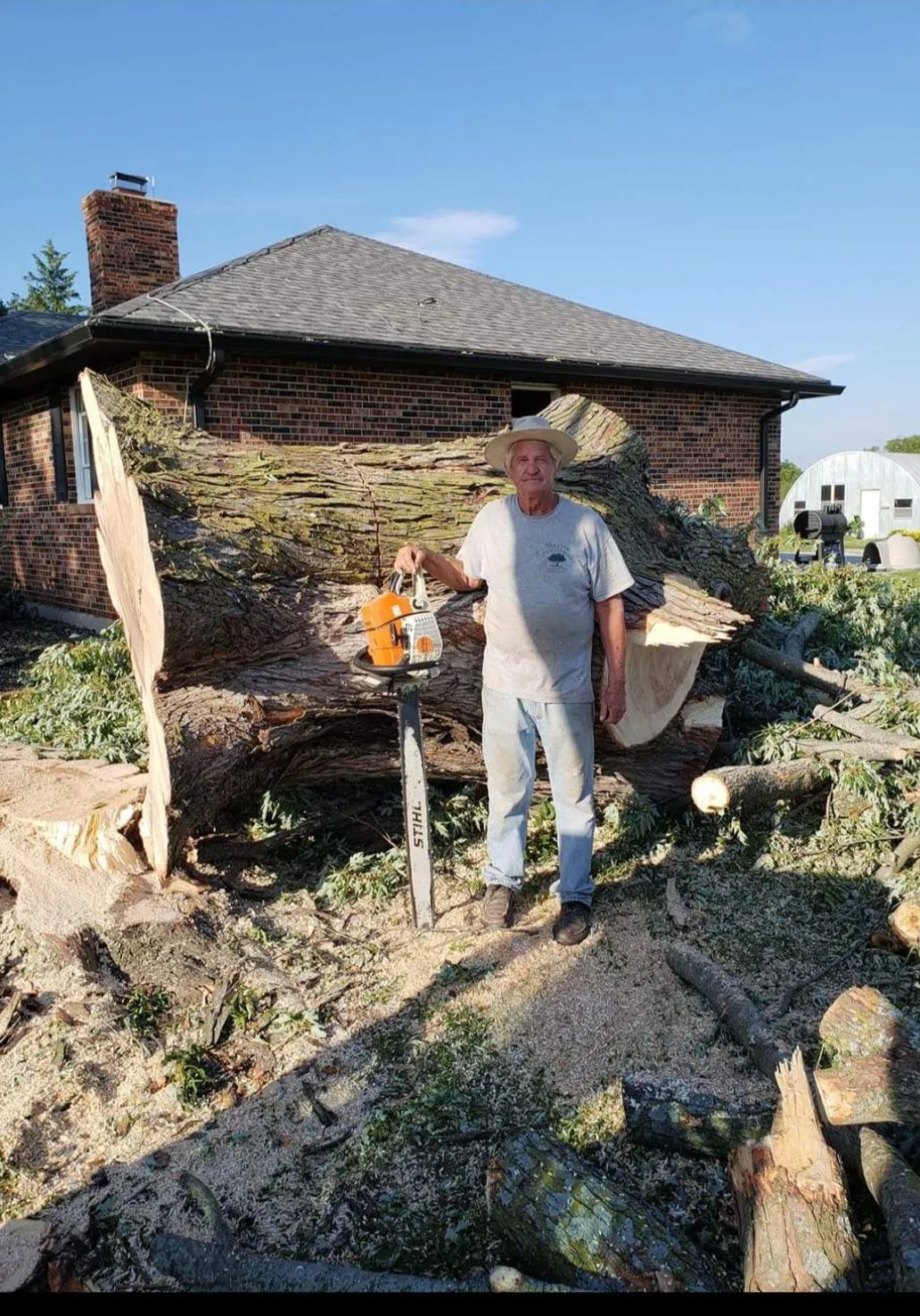 a man is standing in front of a house holding a chainsaw