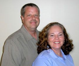 A man and a woman are posing for a picture together and smiling.