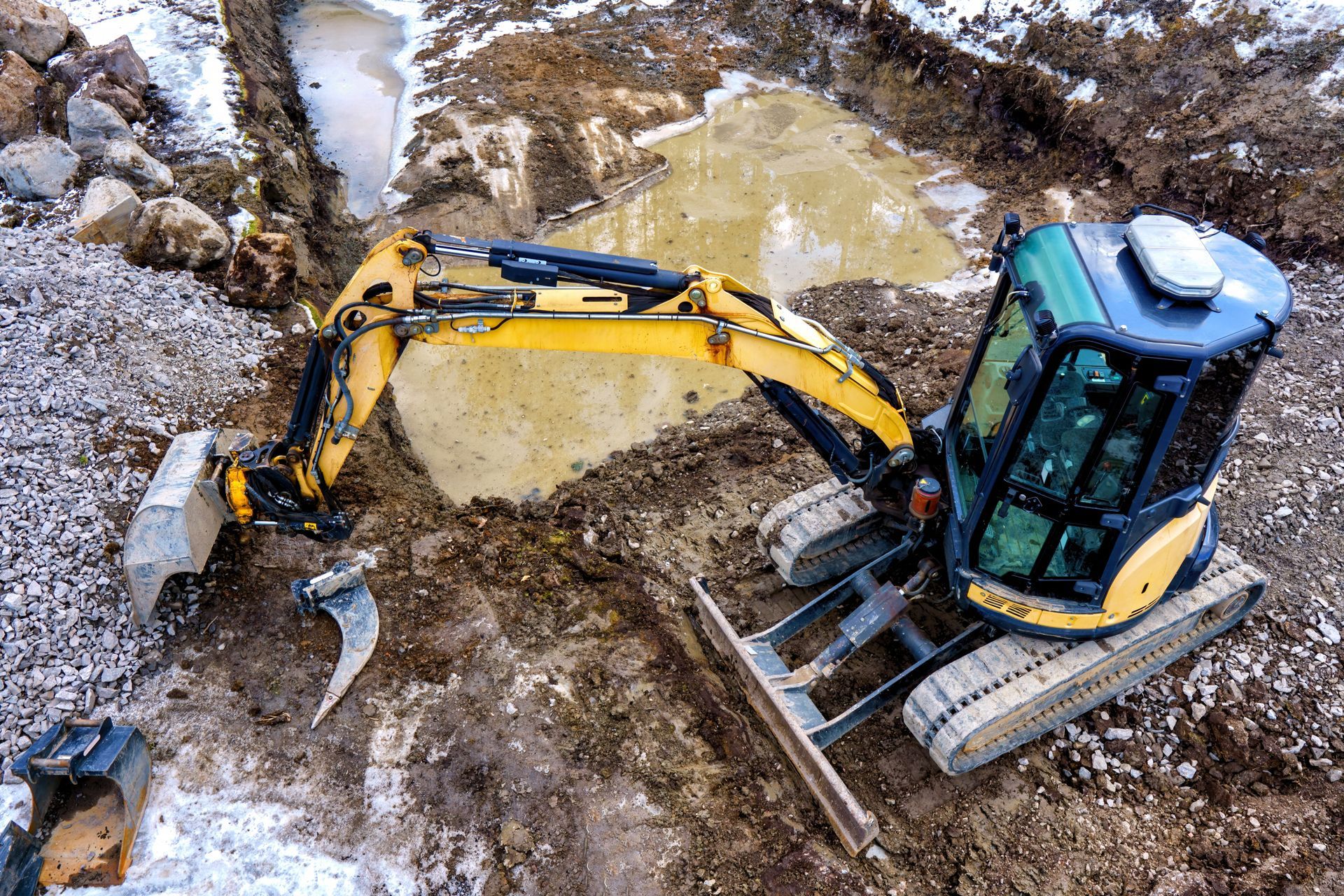 Une excavatrice jaune et noire est assise dans la terre sur un chantier de construction.