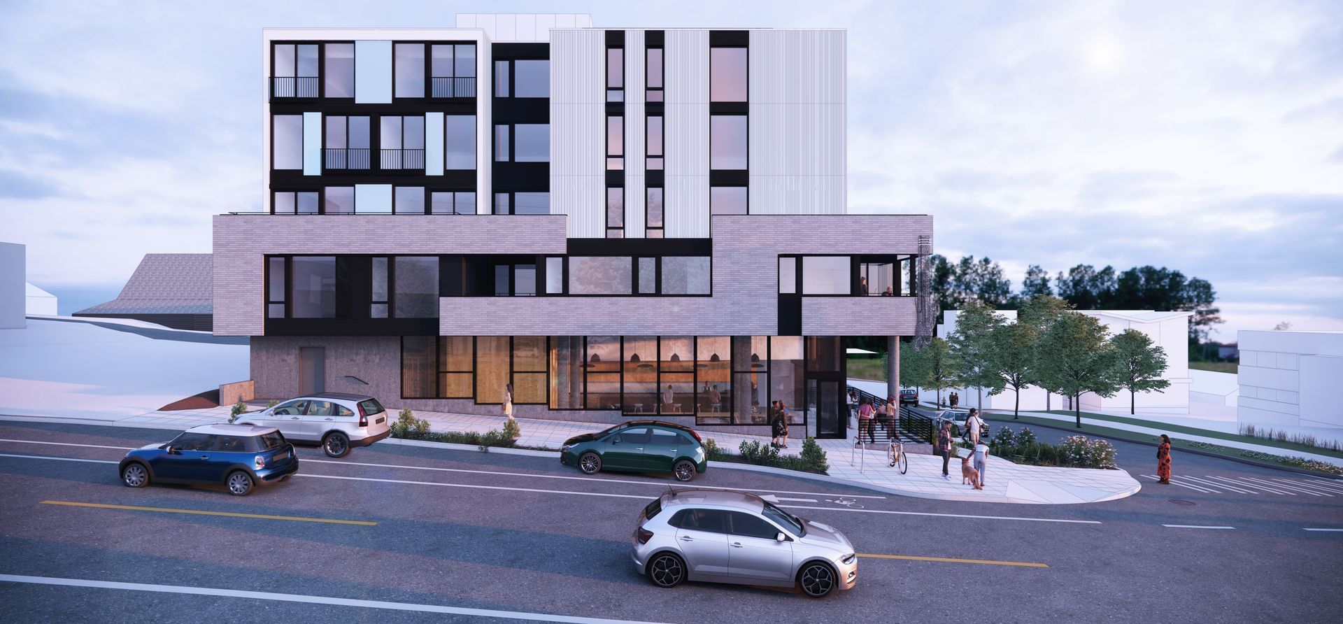 Modern multi-story building with cars on the street in front. Entrance with glass storefront, and trees on the right.