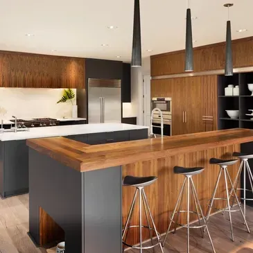 Modern kitchen with wood and black cabinetry, wooden island with stools, and three pendant lights.