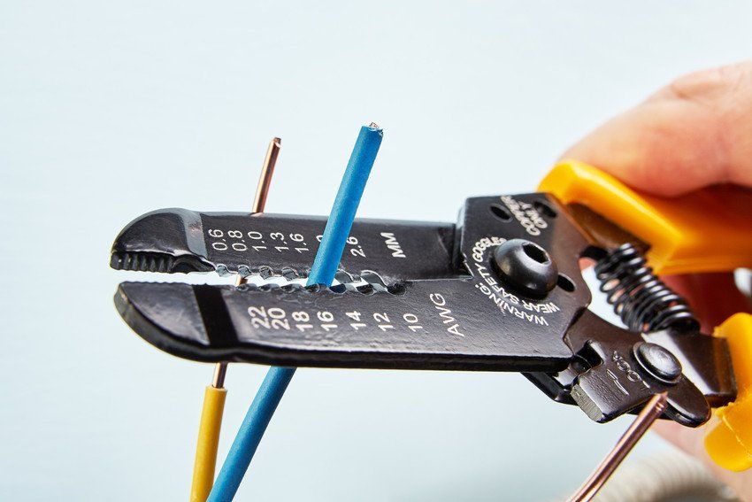 The electrician uses a cutter for stripping wires during electrical work