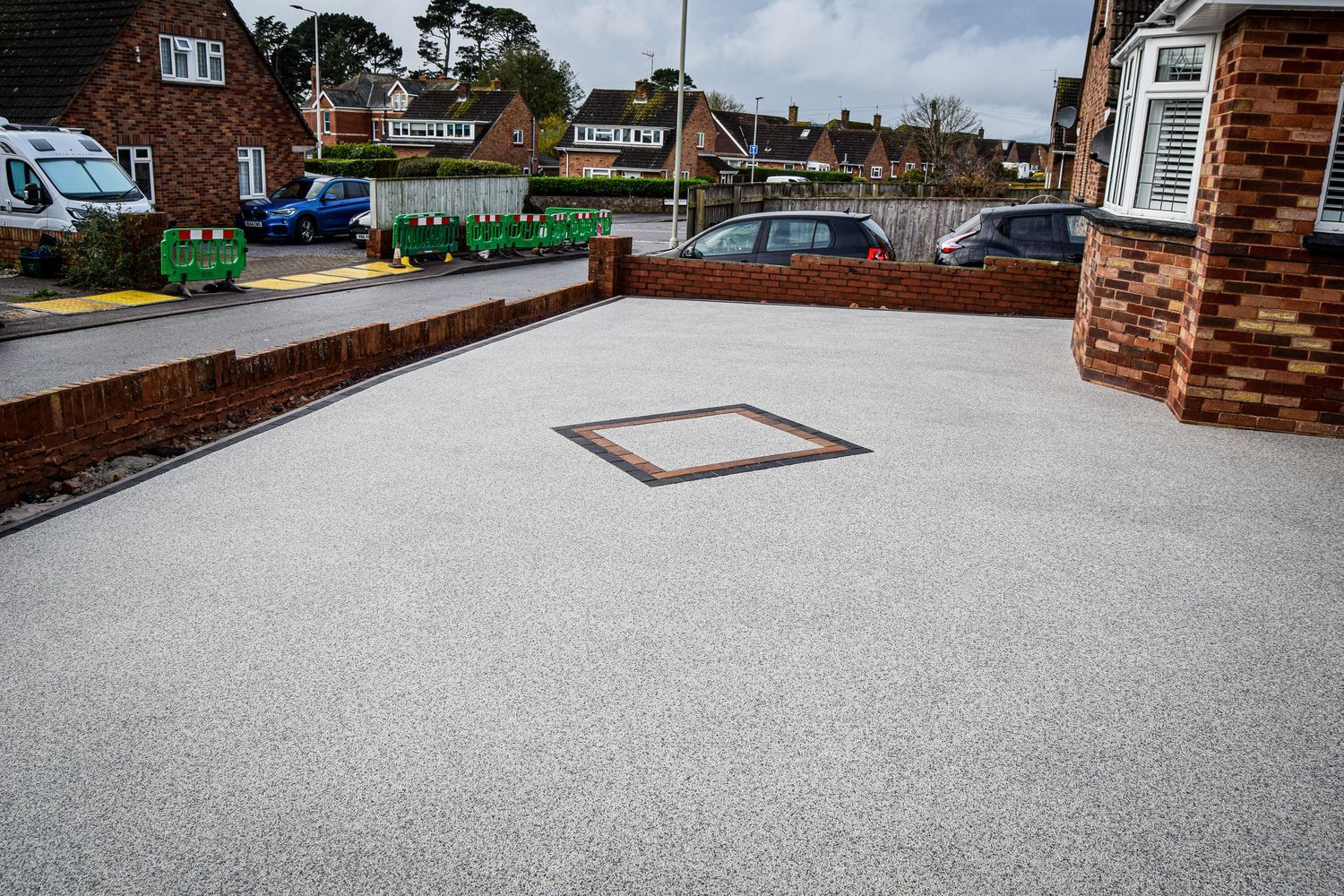 After photo of grey resin driveway in front of red brick house.