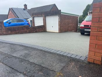 Grey resin driveway with grey block paving border.