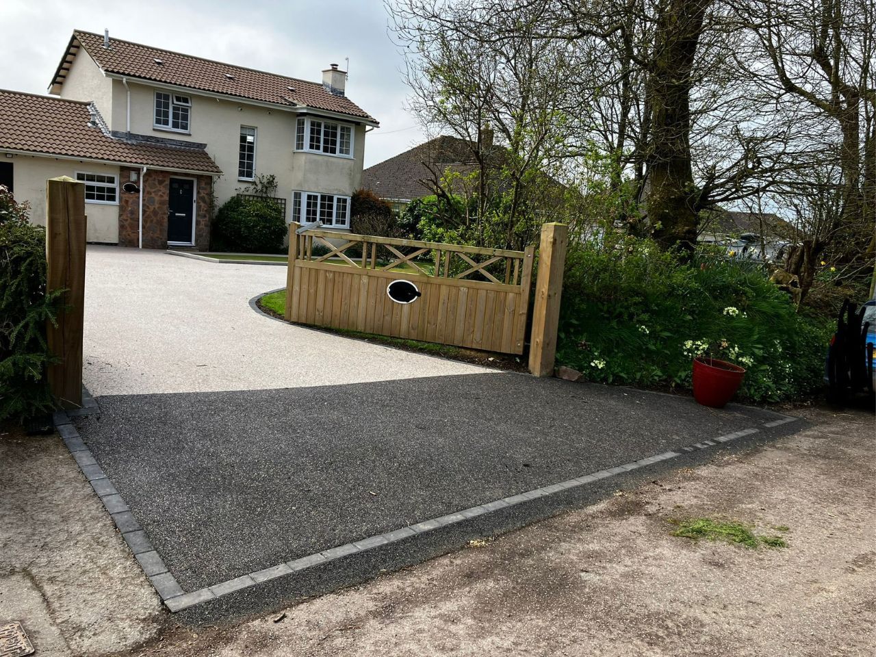 Light resin driveway with two wooden gates open 