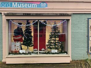 A museum is decorated for christmas with trees in the window.