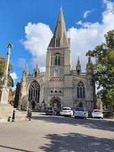 A large church with a clock tower and cars parked in front of it.