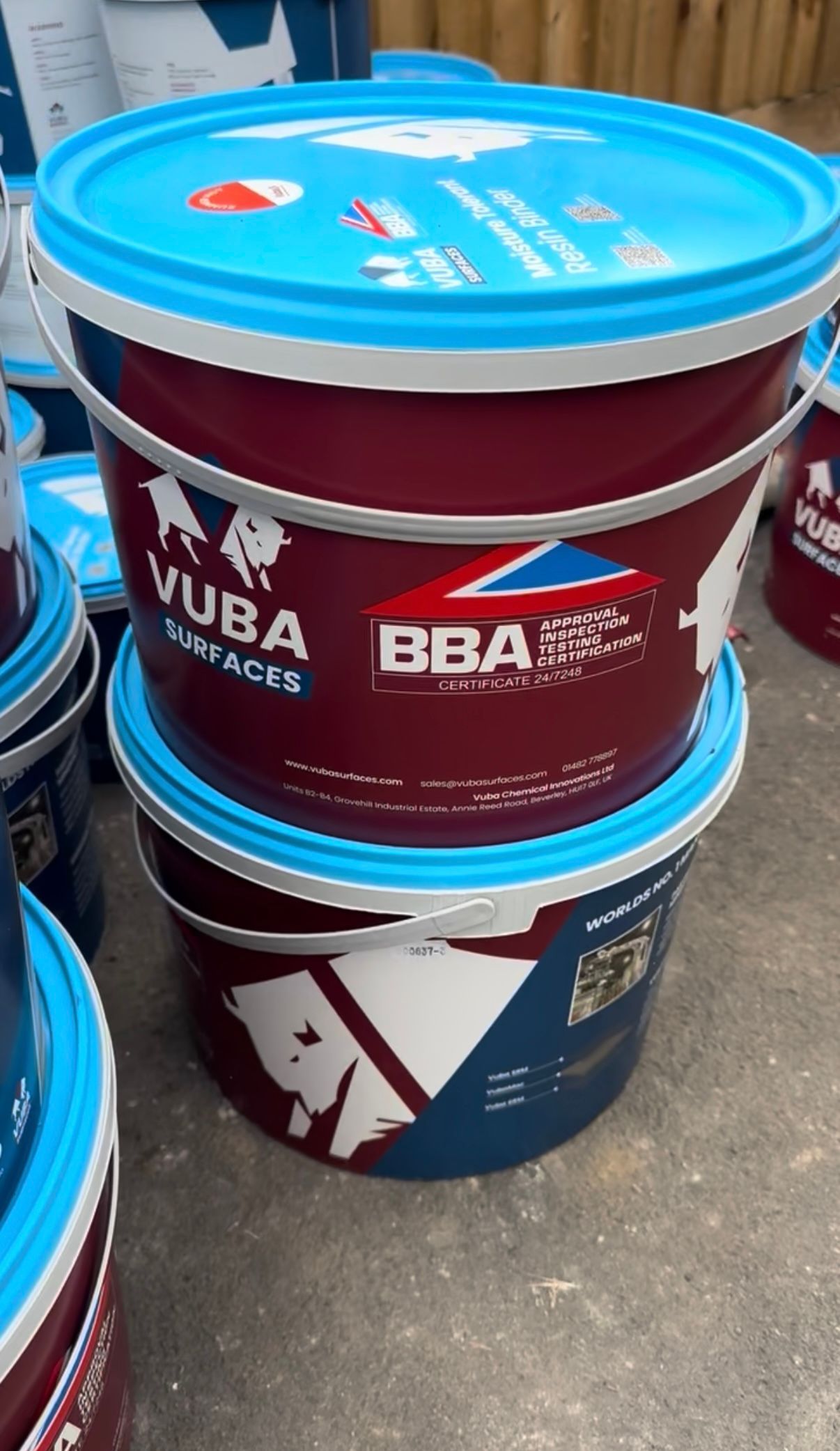 Beige resin driveway leading up to a red brick home with a white door