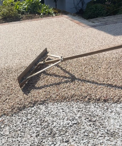 A photo of a fresh, grey resin driveway with a dark block paving border
