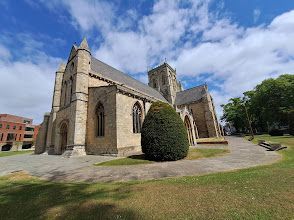 A large church is surrounded by trees and grass on a sunny day.
