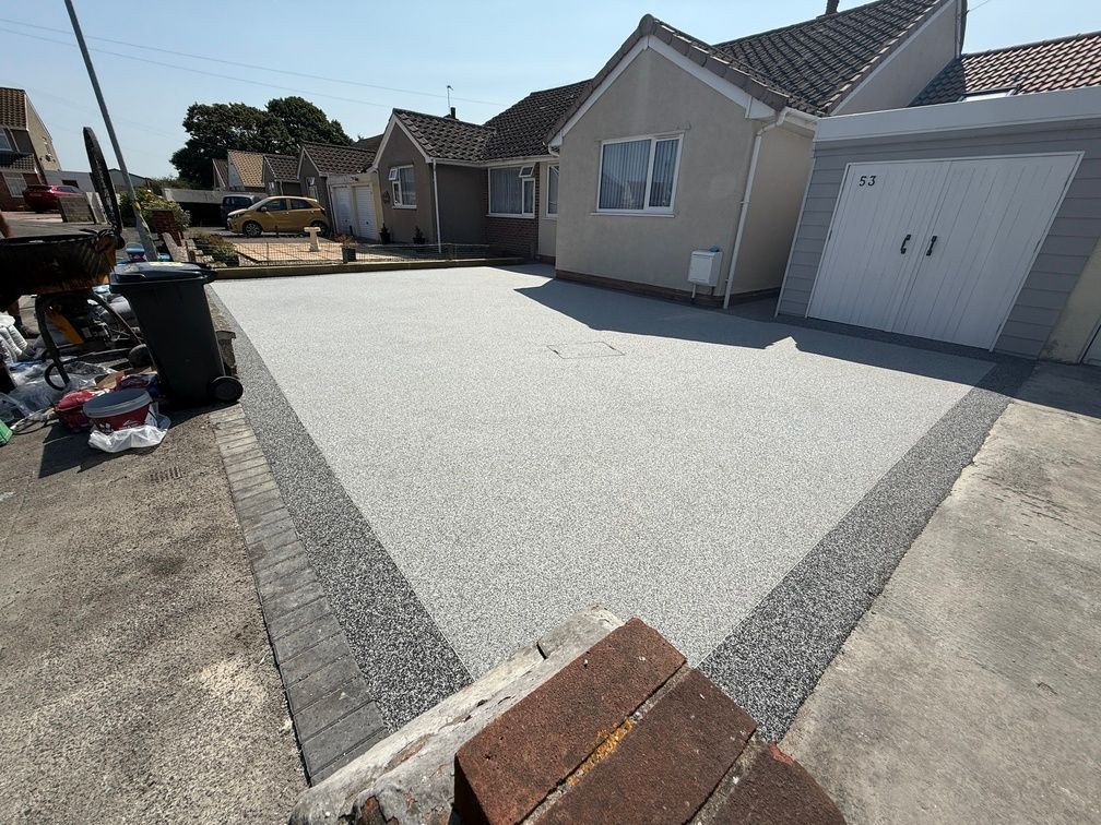 Small brown resin driveway outside cream house