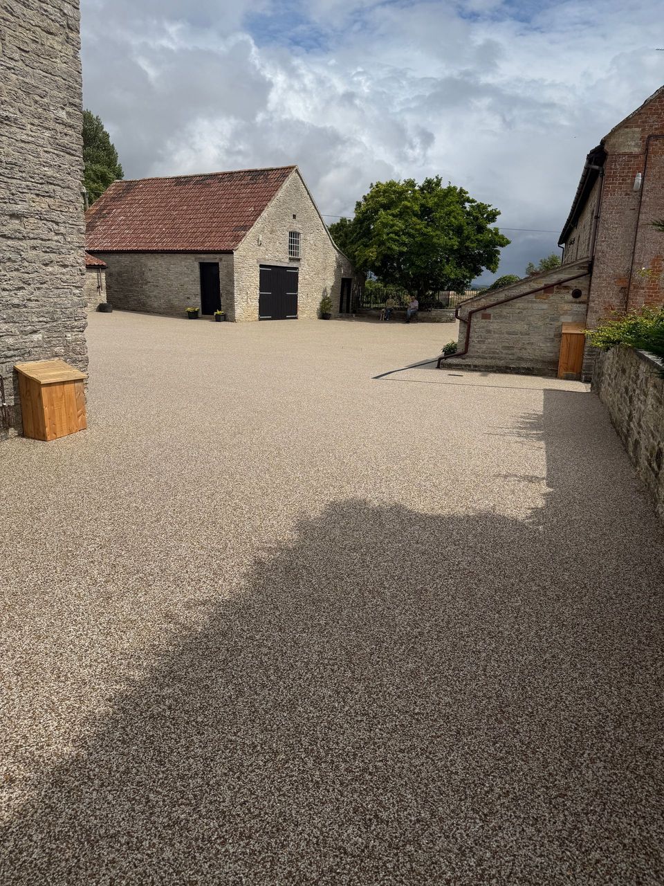 Grey resin driveway with block paving border leading up to mint green door