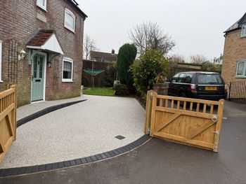 Grey resin driveway with grey block paving border.
