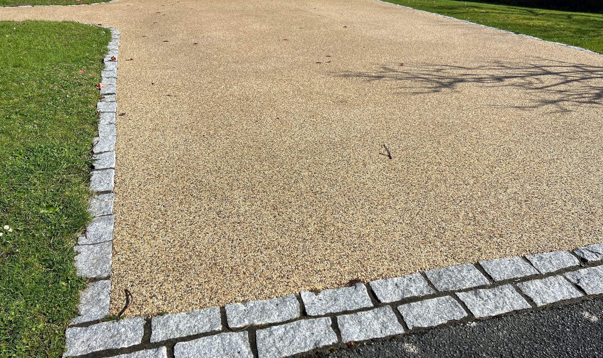 Curved gravel path bordered by grass and gray cobblestones in a park-like setting