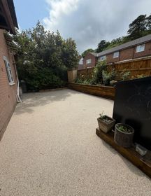 Dark resin driveway with light grey triangular pattern.
