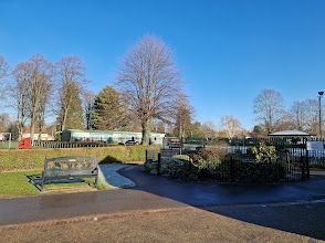 A park with a bench and trees on a sunny day.
