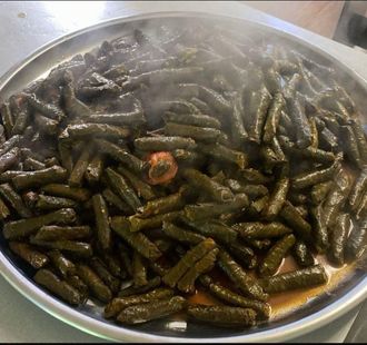 A tray of stuffed grape leaves is steaming on a table