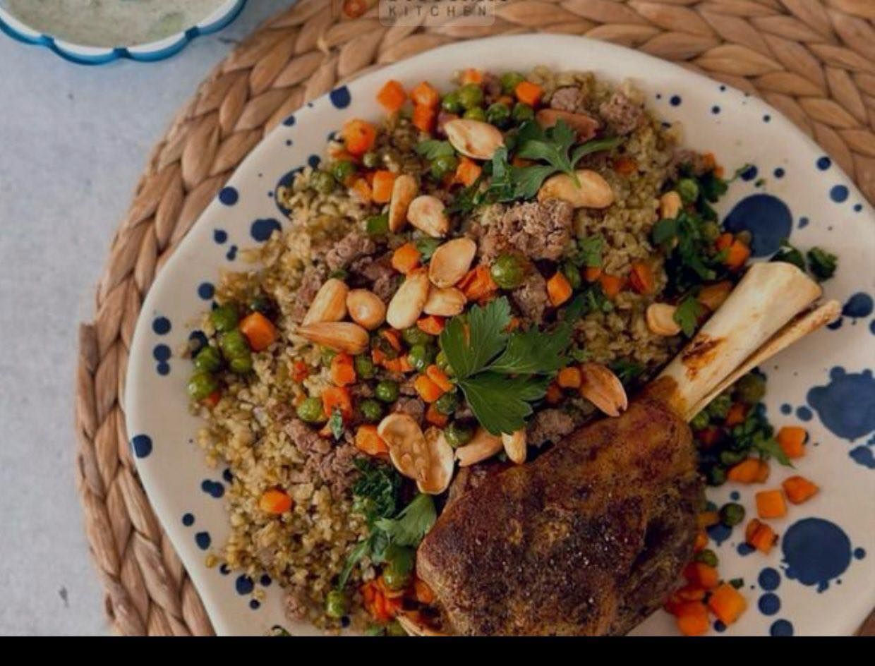 Plate of lamb shank with quinoa, peas, carrots, and almonds.