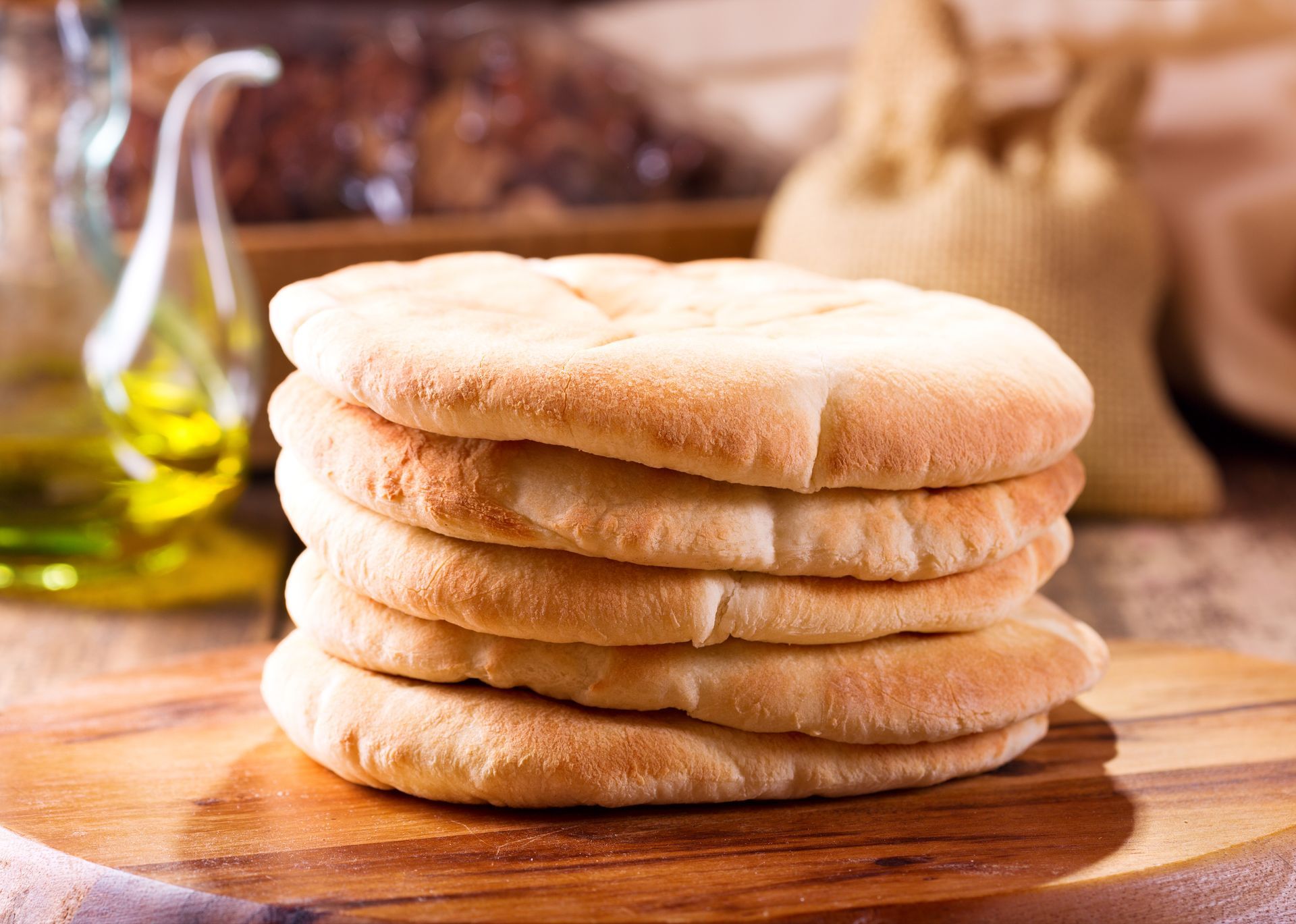 A stack of pita bread on a wooden cutting board.