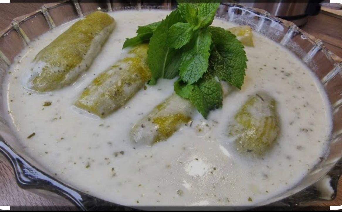 A bowl of soup with vegetables and mint leaves on top.