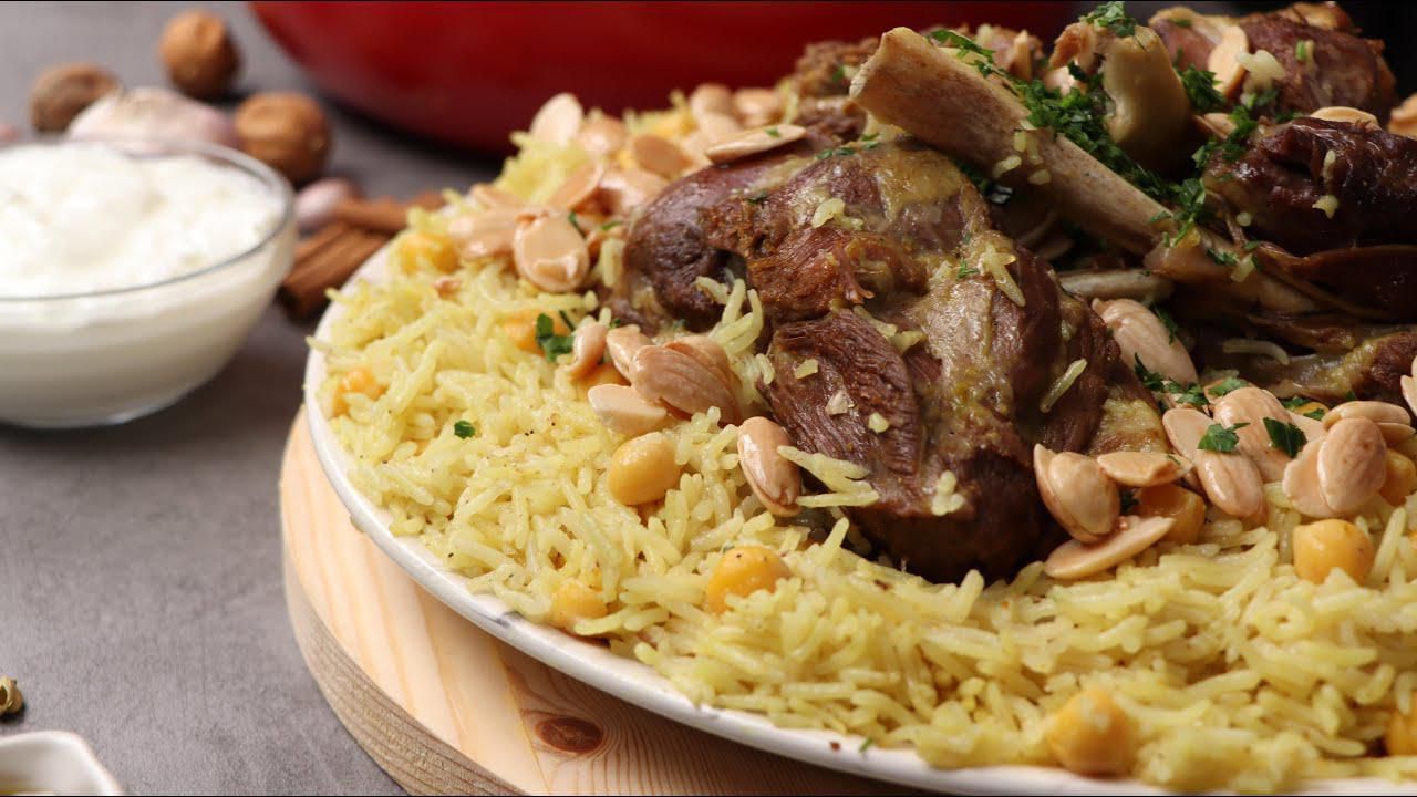 Lamb and rice dish, garnished with almonds and parsley, served with yogurt.