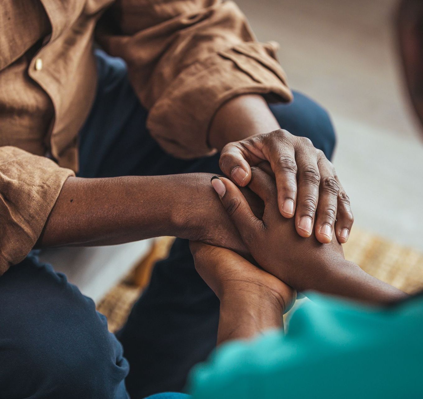 A person is holding another person 's hand while sitting on a couch.