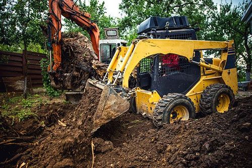 A bulldozer and an excavator are digging a hole in the ground.