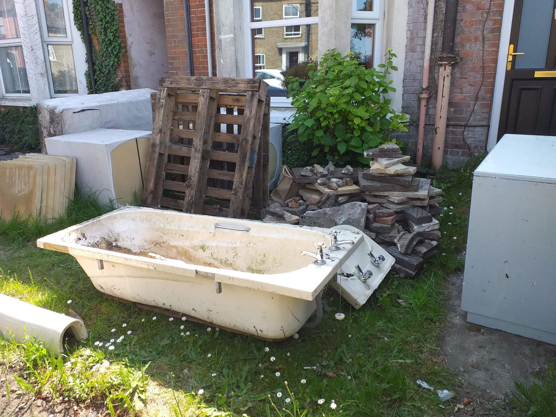 an old bath, wood and varios items out for collection