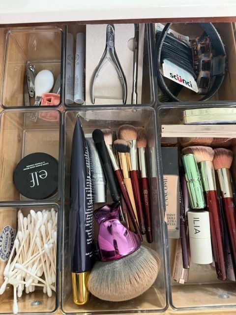 Assorted makeup brushes and cosmetic tools organized in clear compartment trays.