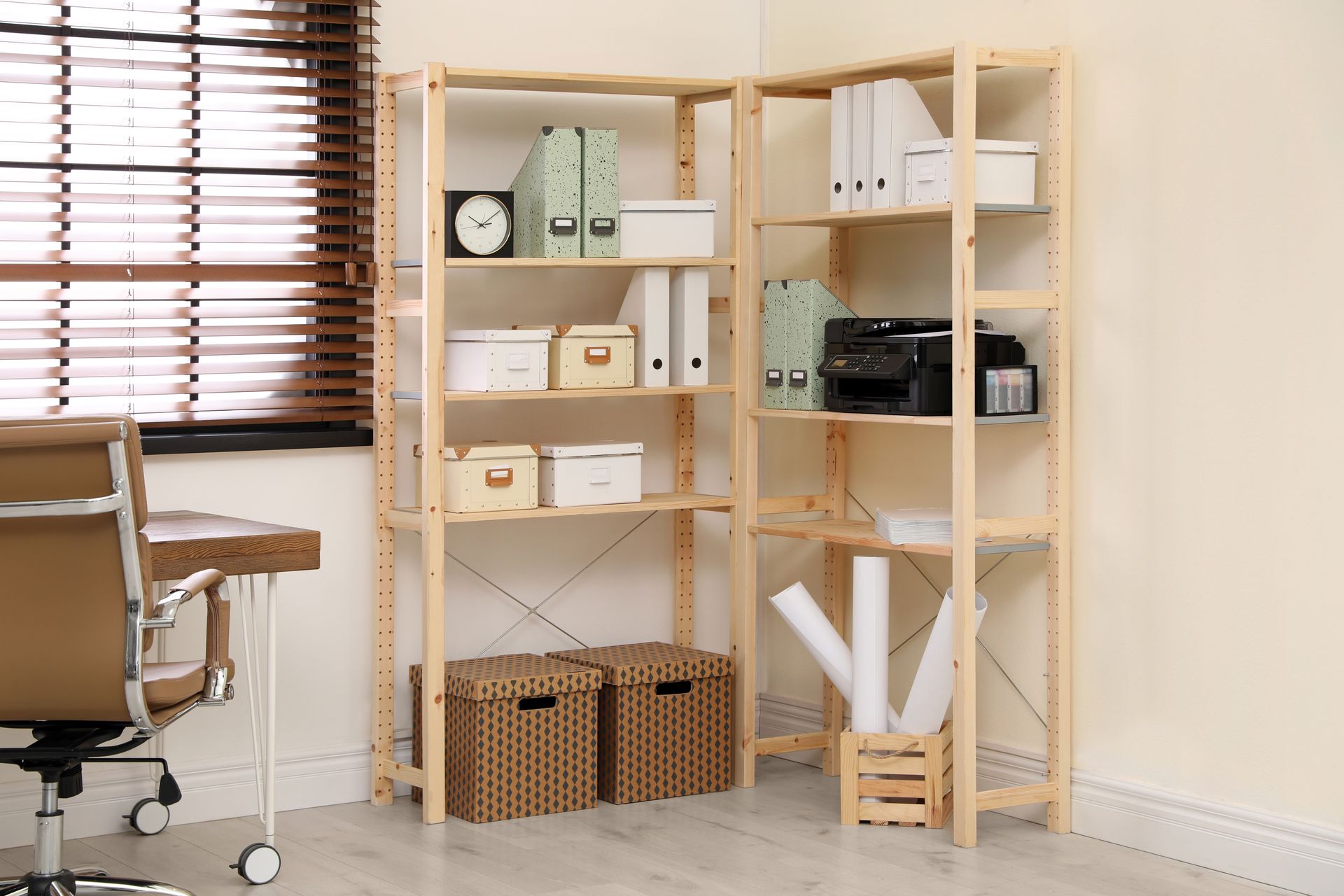 Home office corner with shelving, storage boxes, and a desk by a window with blinds