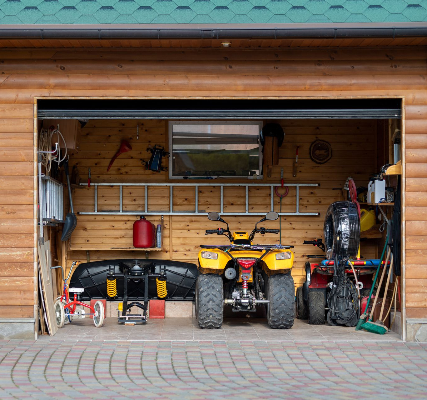 Garage with a yellow ATV, tools, and storage items on wooden shelves and brick floor