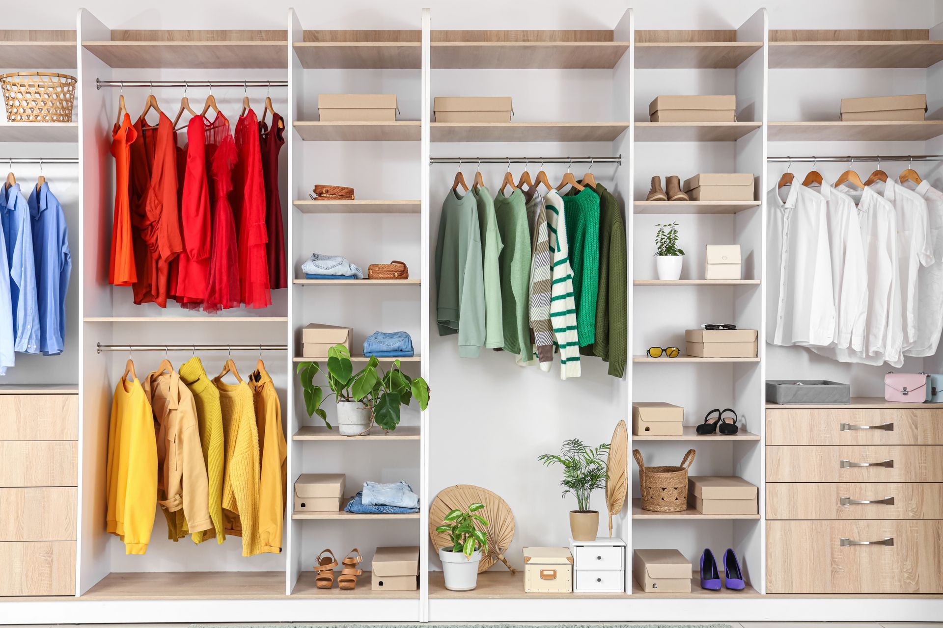 Open closet with colorful hanging clothes, shelves, and drawers in a bright wardrobe room