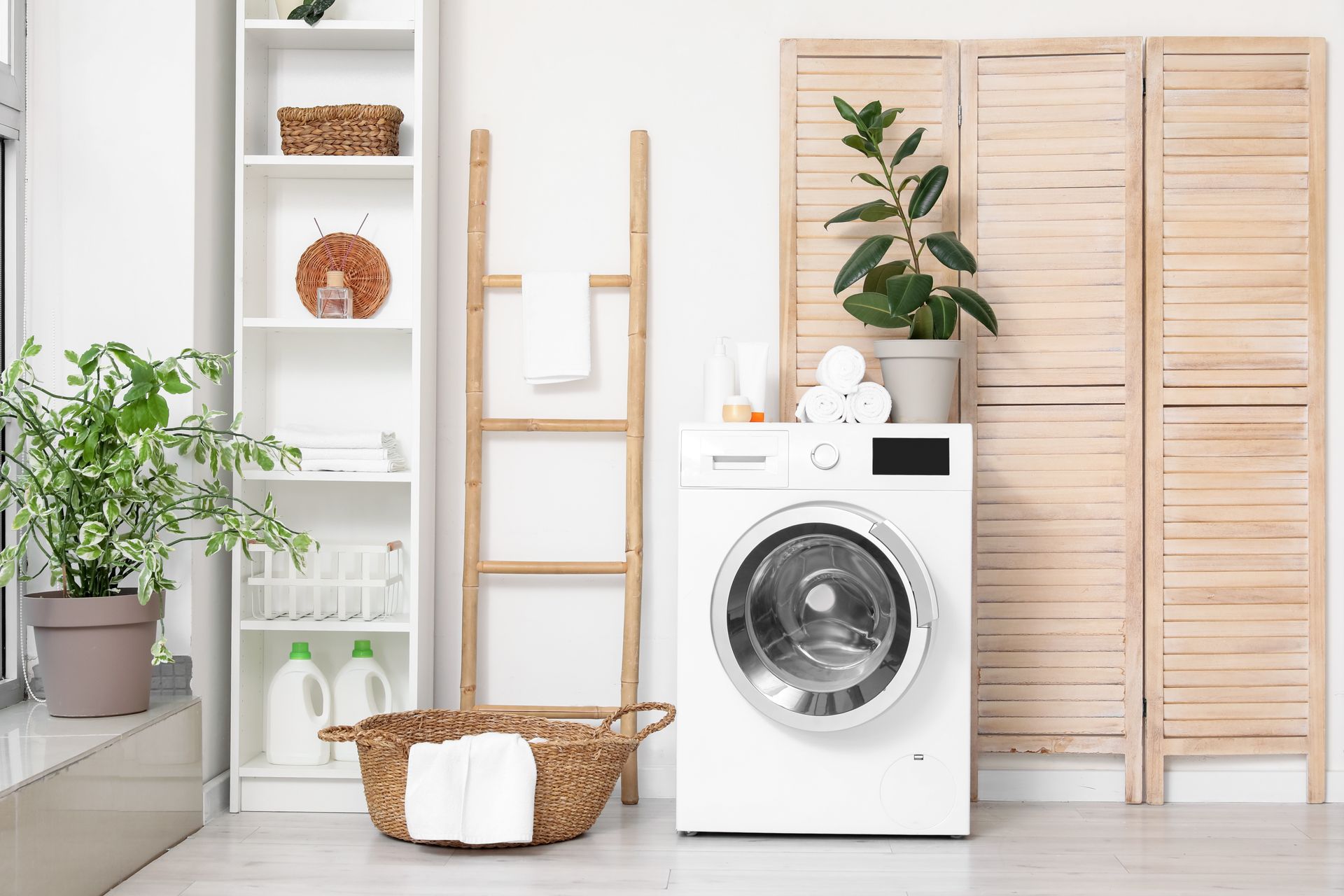 Bright laundry room with washing machine, wicker basket, plants, and wooden shelving.