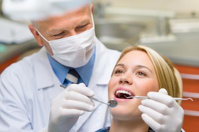 Dentist examining a woman's teeth in a dental office.