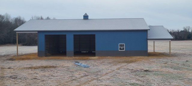 A blue and gray building is sitting in the middle of a field.