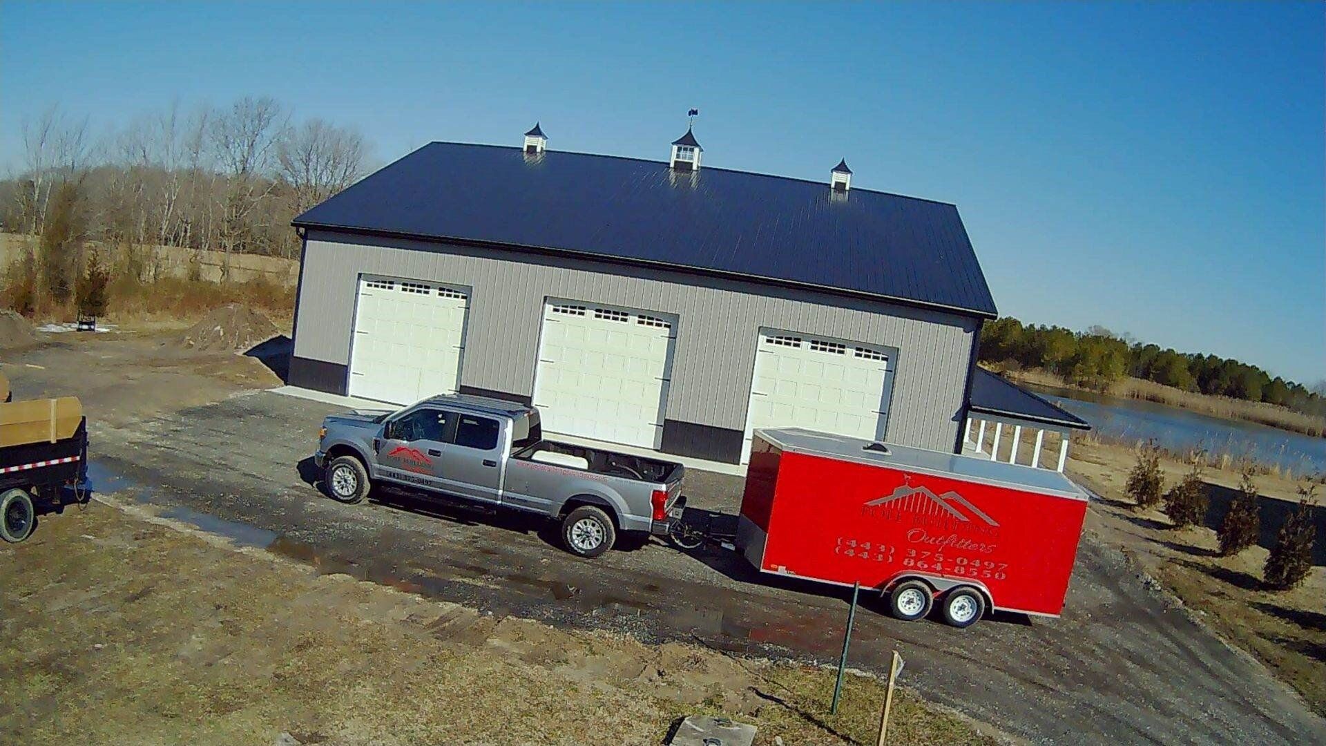 An aerial view of a truck pulling a trailer in front of a building.