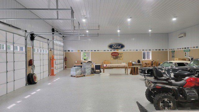 A large garage with a lot of cars and atvs parked in it.