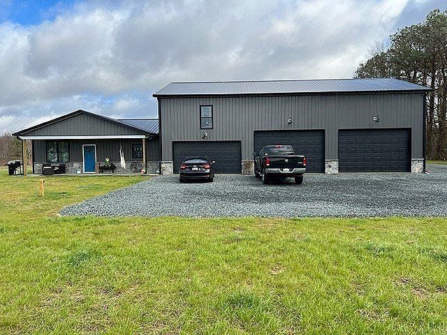 Two cars are parked in front of a large house with three garages.