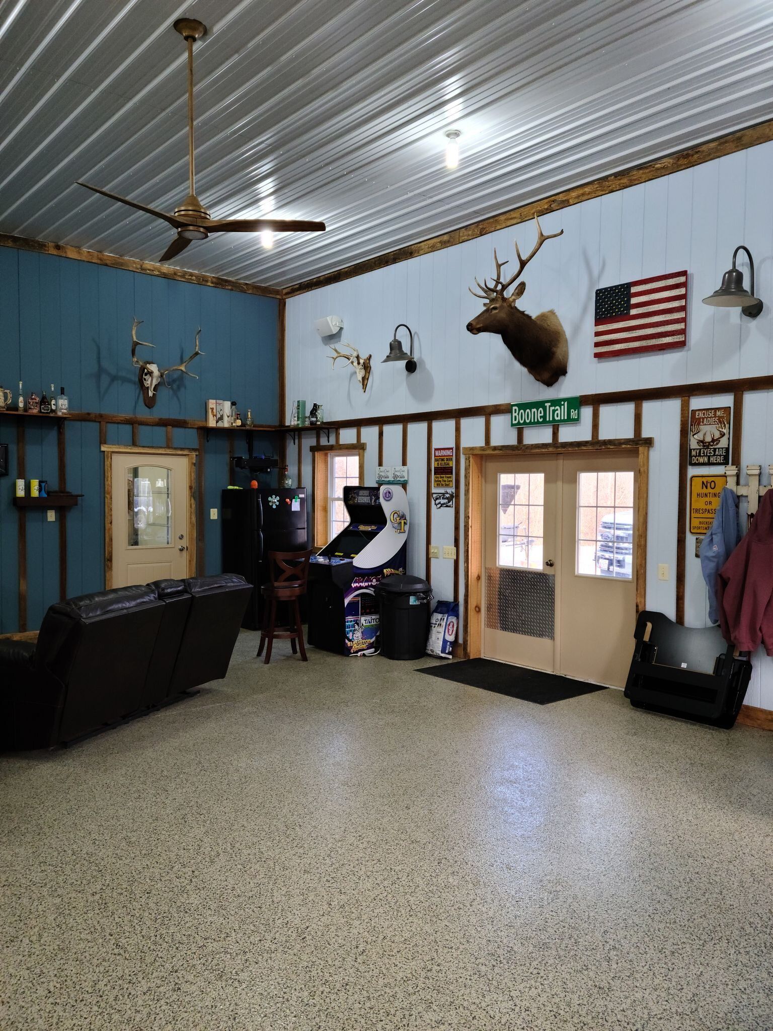 A large room with a ceiling fan and a deer head on the wall.